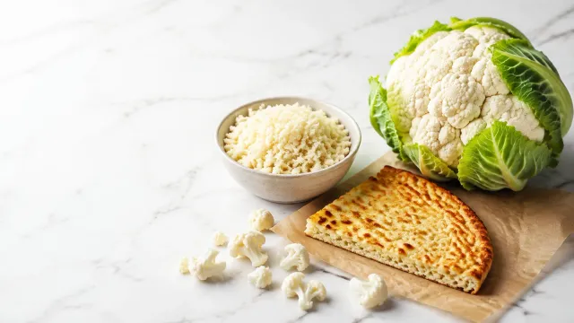 Keto Lebensmittel: frischer Blumenkohl, daneben Blumenkohlreis und ein Blumenkohl-Pizzaboden