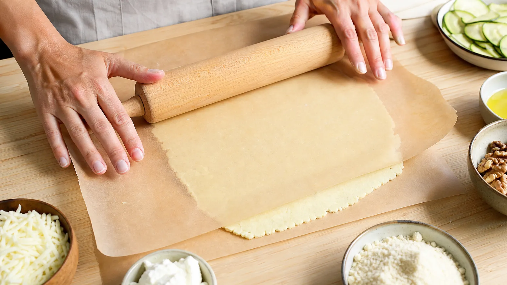 Der Mandel-Mozzarella-Teig wird zwischen Backpapier dünn ausgerollt