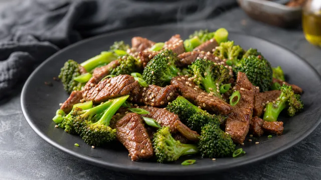 Keto Rindfleisch-Brokkoli aus dem Wok mit Sesamkörnern auf einem dunklen Teller angerichtet