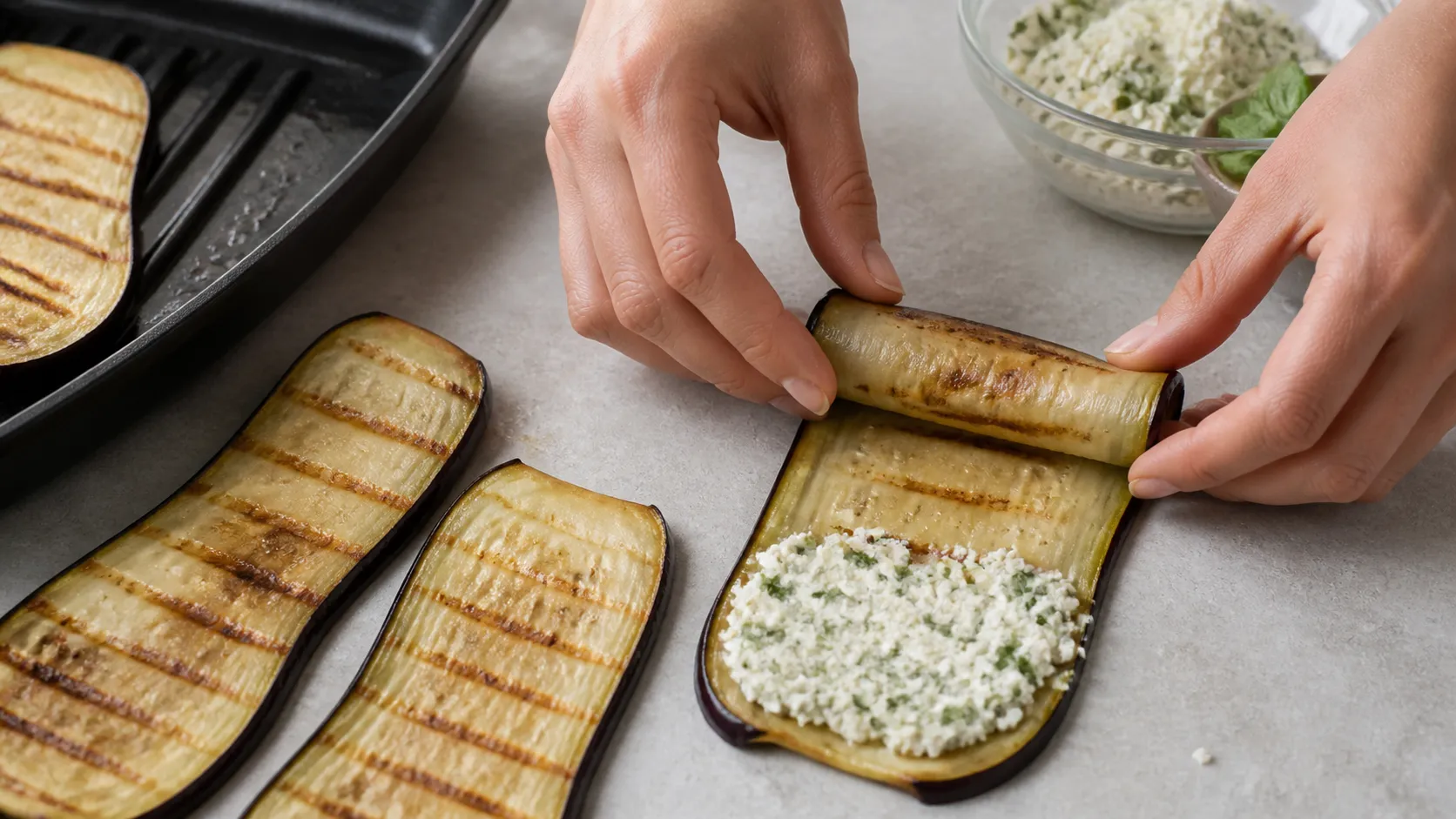 Gegrillte Auberginenscheiben werden am unteren Ende mit Ricottafüllung bestrichen und aufgerollt