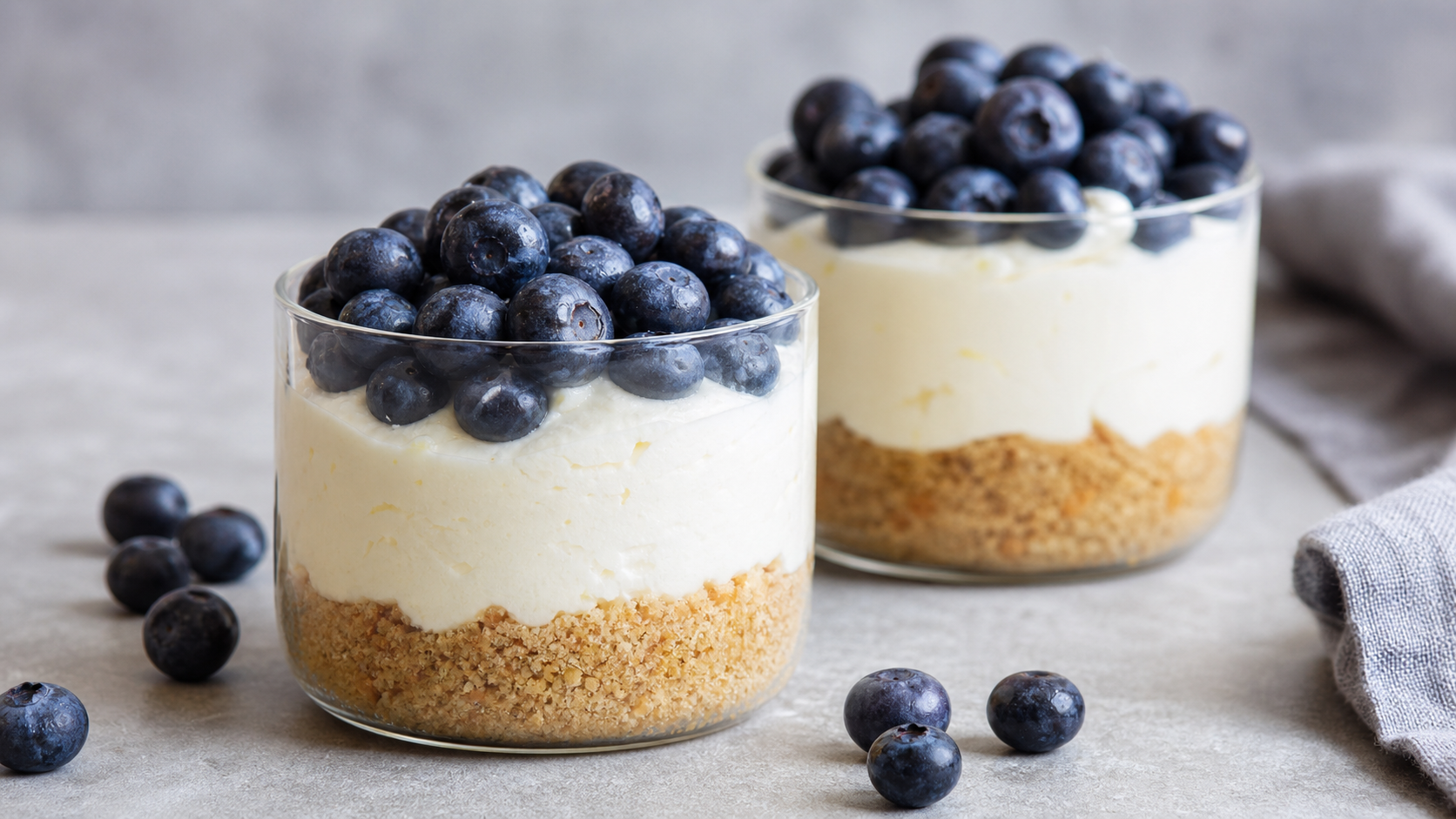 Cremiger Keto-Käsekuchen im Glas mit Mandelboden, Frischkäsecreme und frischen Blaubeeren obenauf