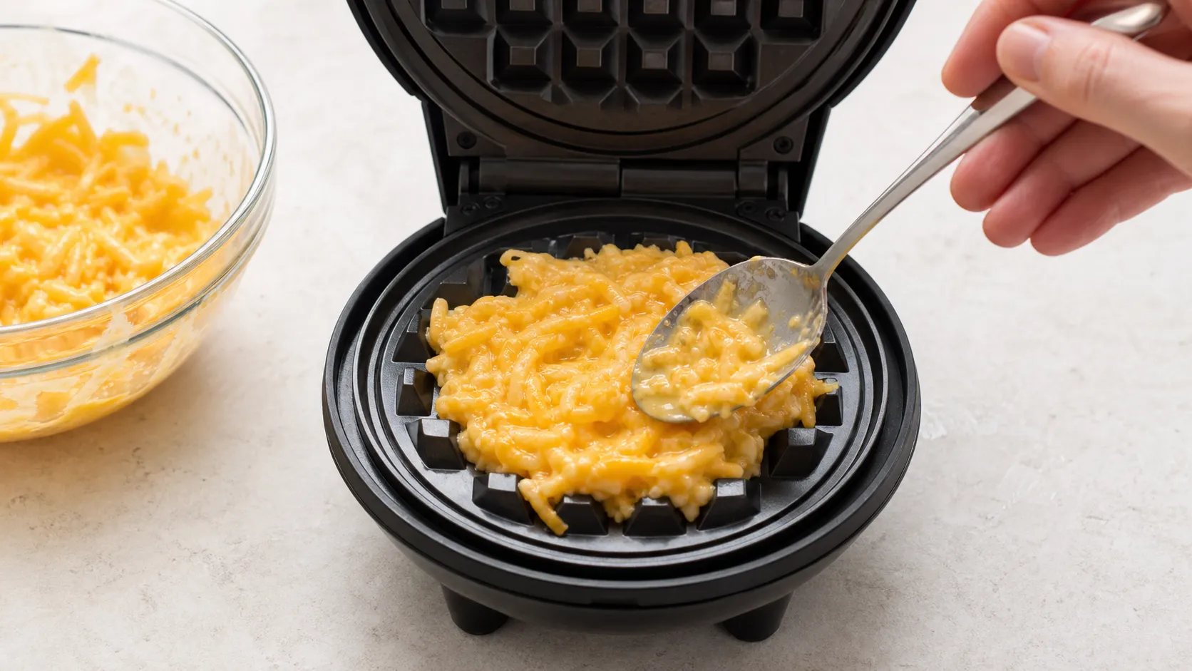 Käse-Ei-Masse wird in ein kleines Waffeleisen gefüllt