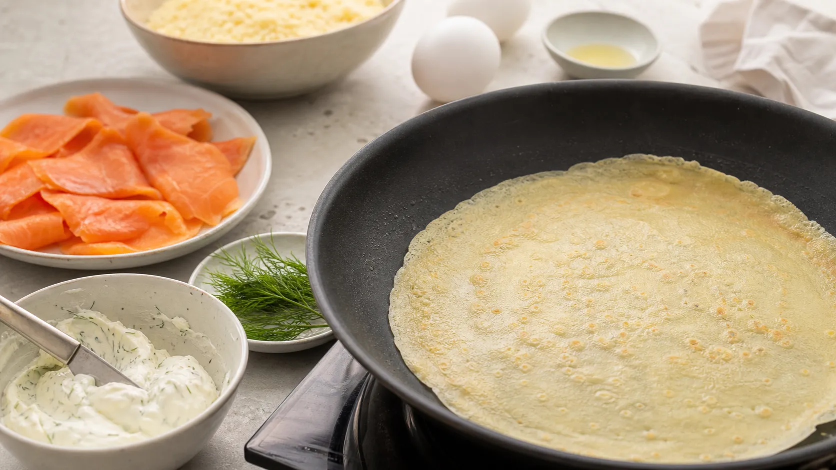 Dünner Mandelmehl-Crêpe in einer beschichteten Pfanne, daneben die vorbereitete Füllung