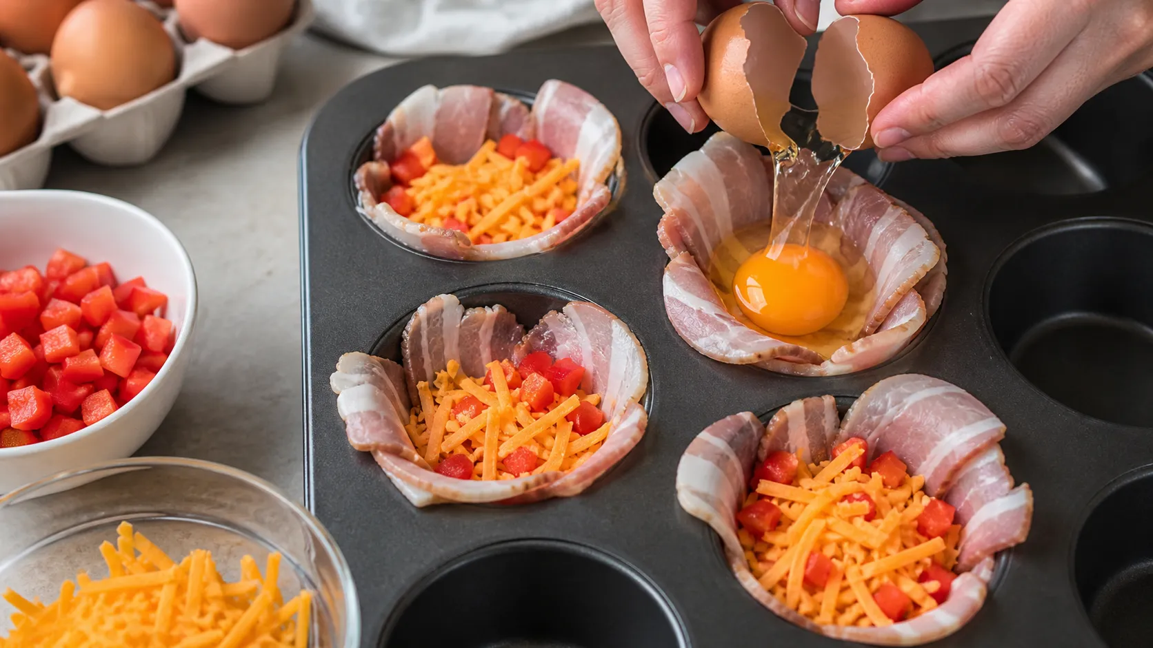 Frühstücksspeck im Muffinblech mit Cheddar und Paprika füllen und ein Ei aufschlagen