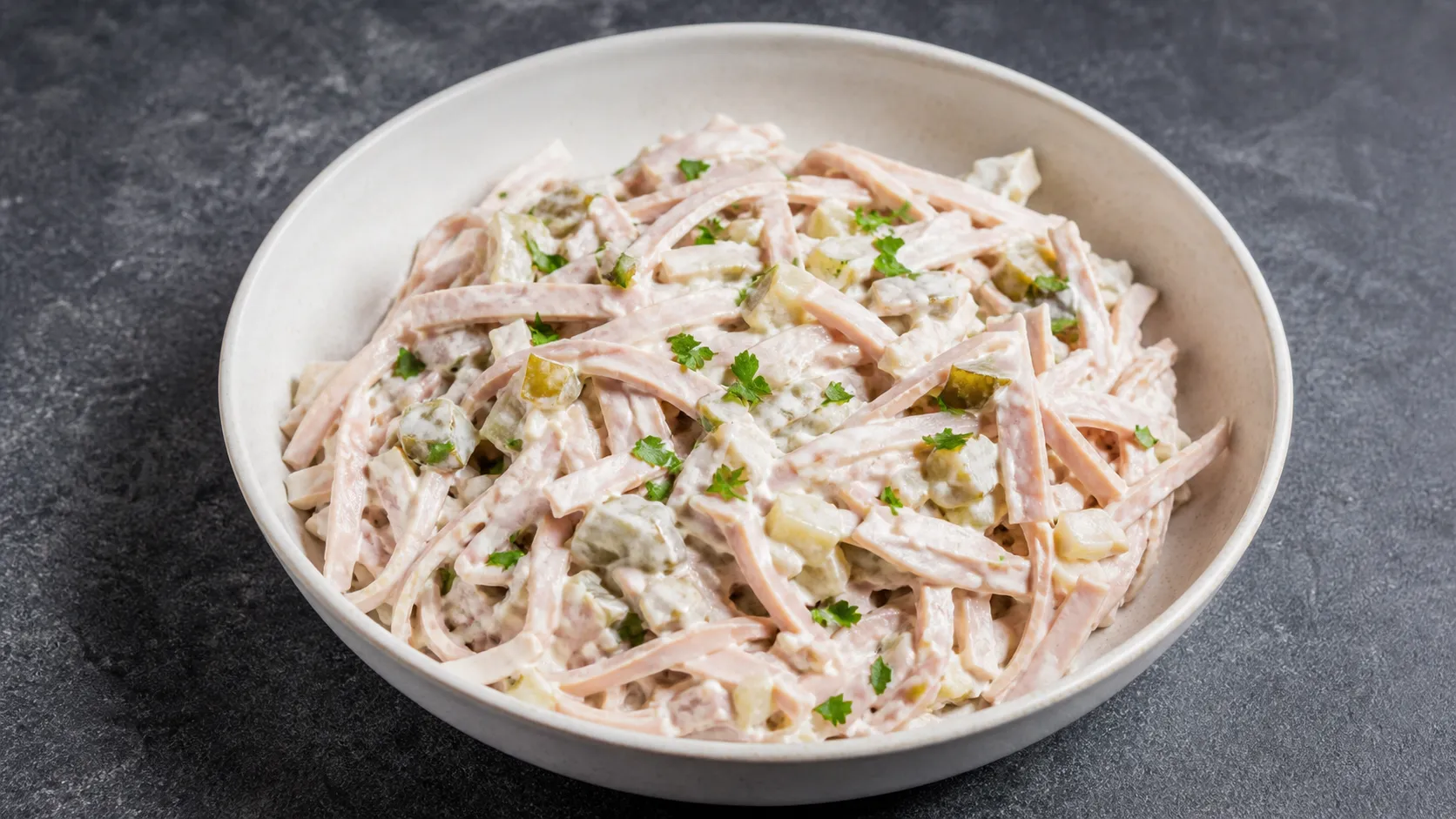 Cremiger Keto-Fleischsalat aus Fleischwurststreifen, Mayonnaise und Gewürzgurke in einer Schüssel mit Petersilie