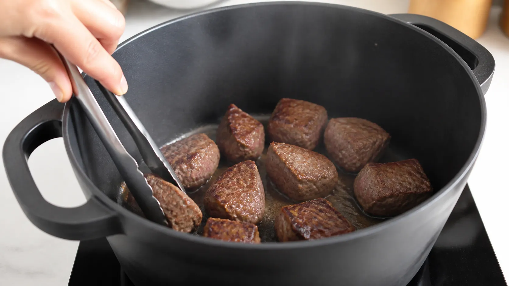 Rindfleischwürfel braten in einem großen Topf kräftig an, bevor die Brühe angegossen wird