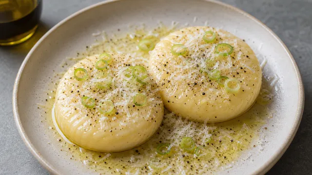 Keto-Handkäse mit weißem Trüffelöl, Parmesan, Frühlingszwiebeln und schwarzem Pfeffer auf einem Teller