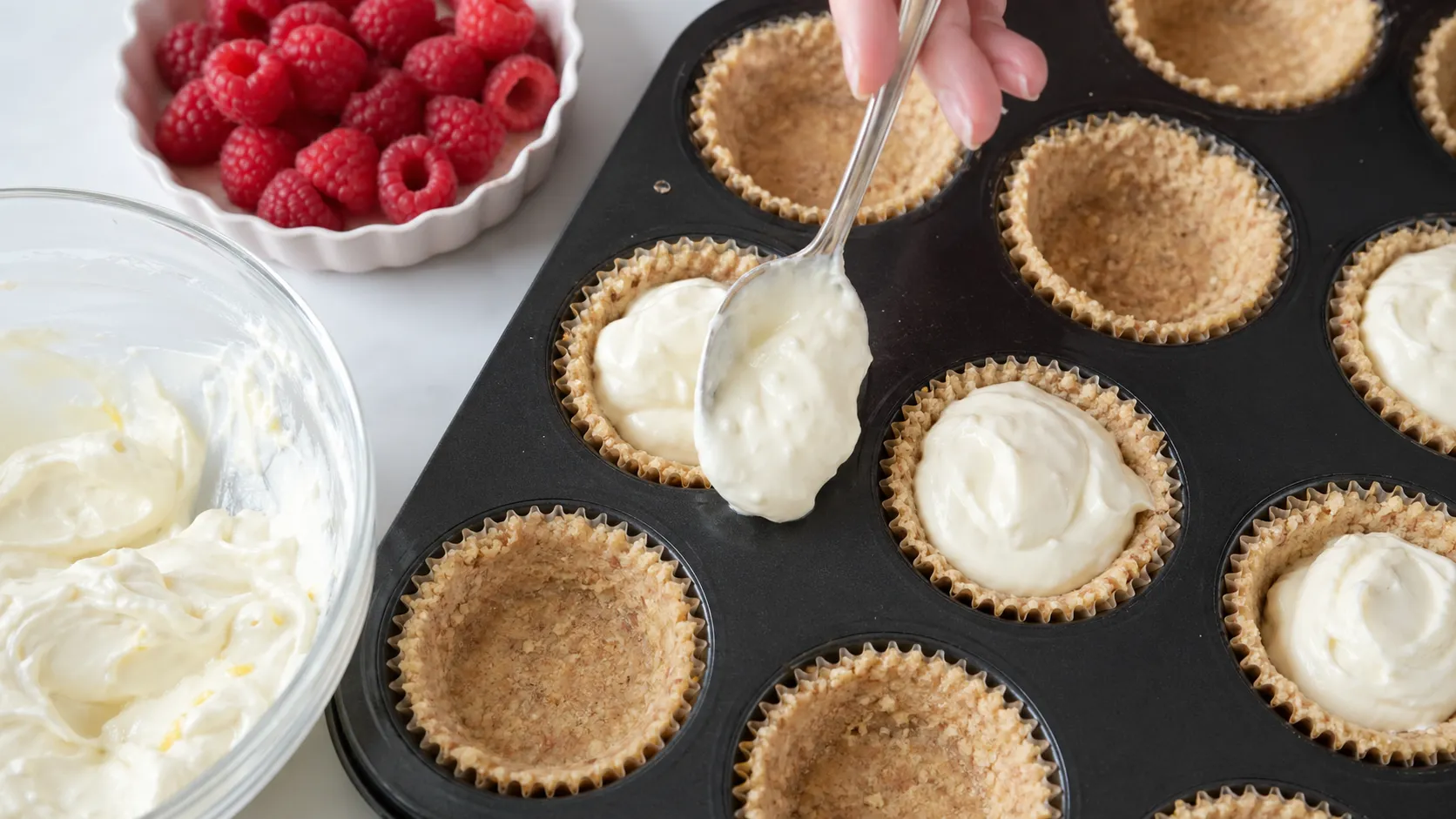 Frischkäsecreme in die vorbereiteten Mandelboden-Förmchen für die Keto-Bites füllen