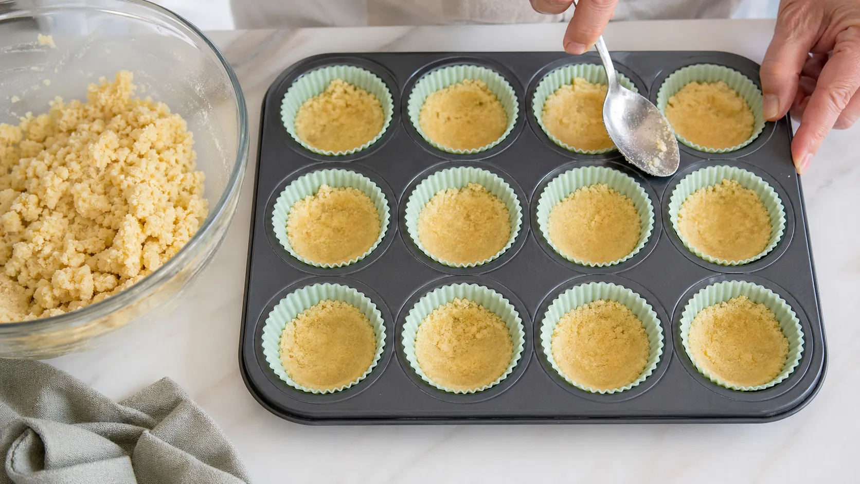 Mandelmehl-Butter-Boden in Muffinförmchen drücken für die Keto Käsekuchen-Bites