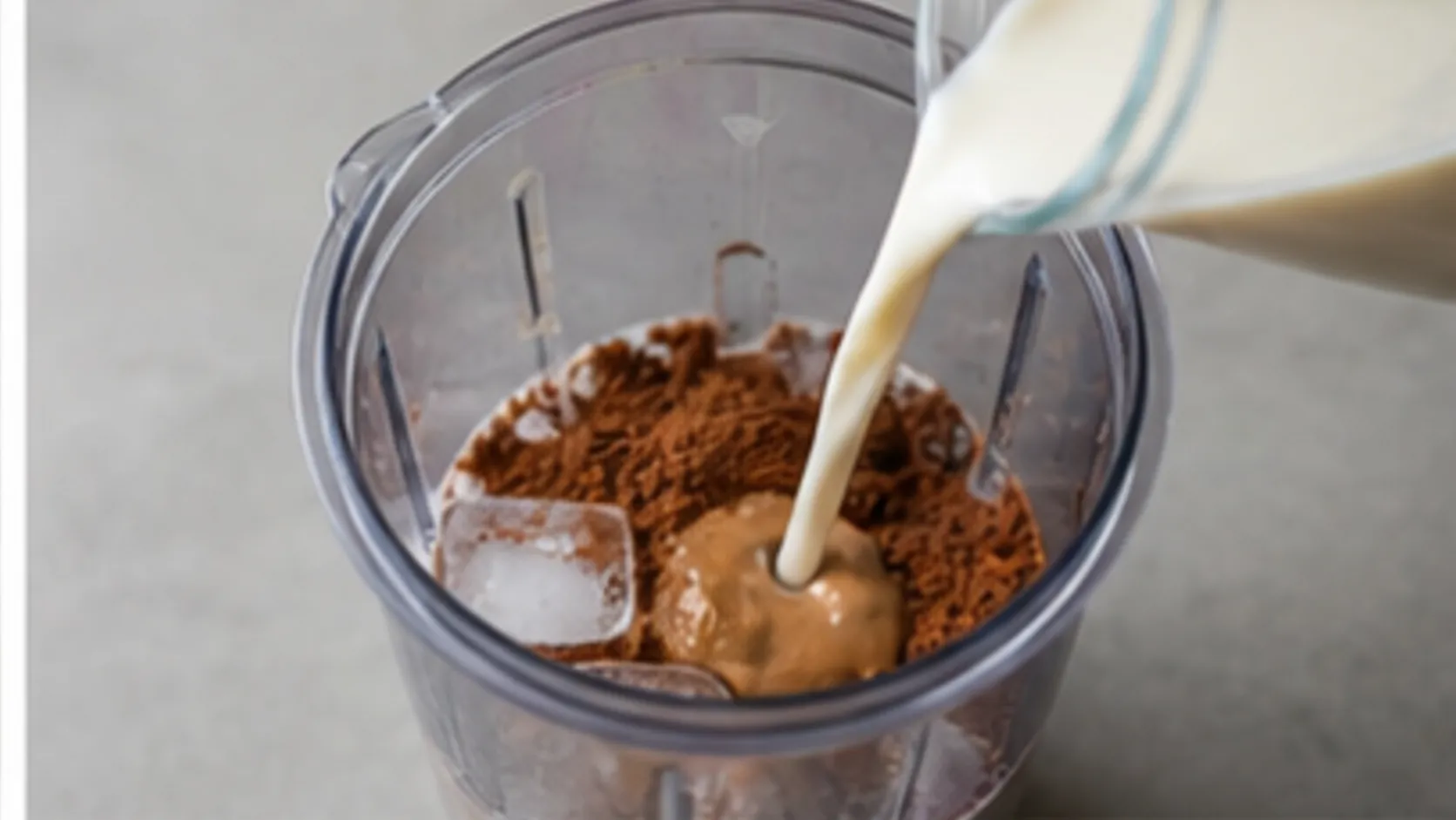Mandeldrink wird in einen Mixer mit Mandelmus, Backkakao und Eiswürfeln gegossen