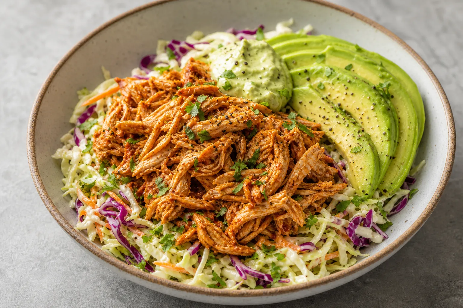 Fertige Keto Pulled Chicken Bowl mit Krautsalat und Avocado angerichtet