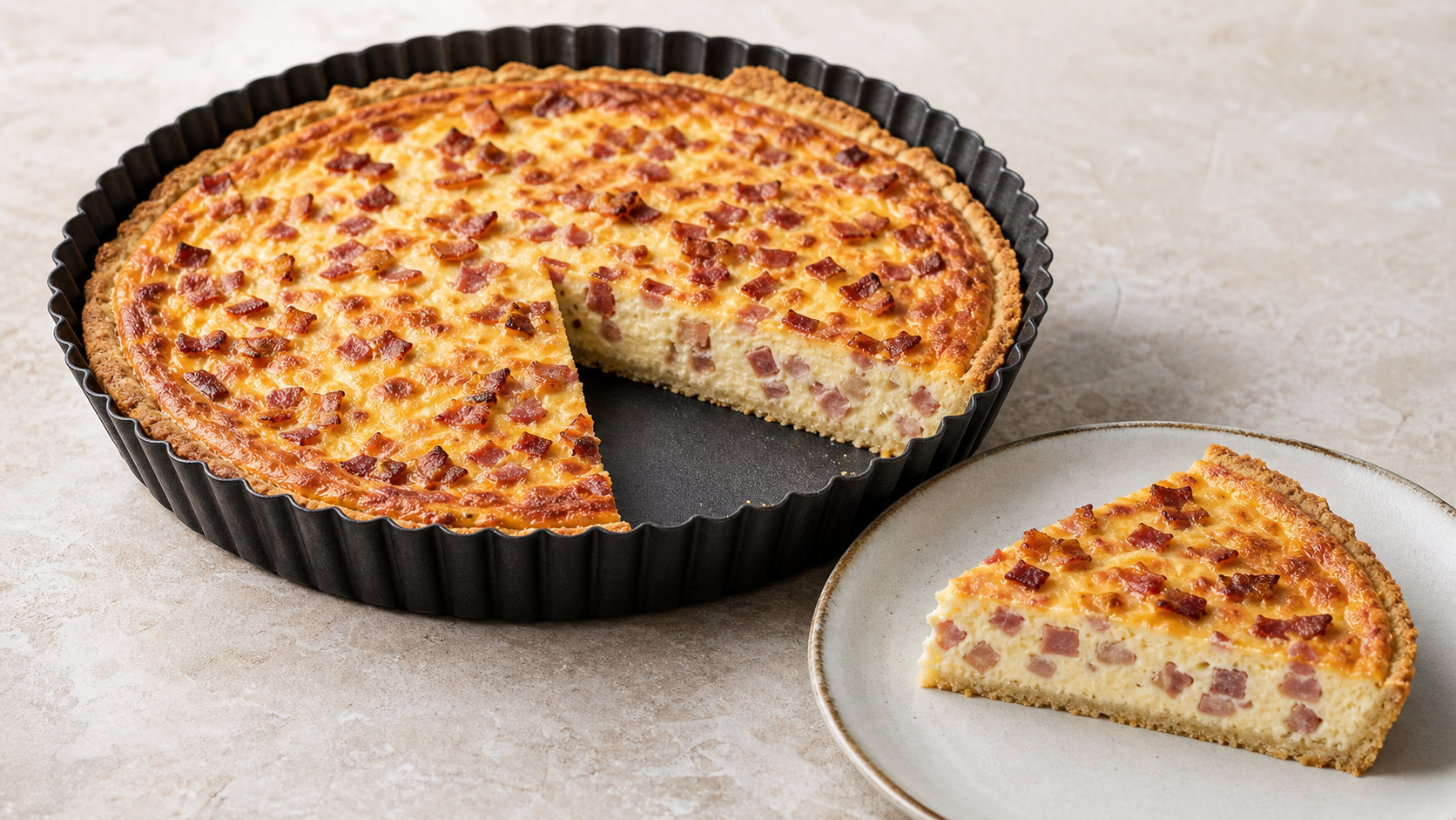 Angeschnittene Keto-Quiche Lorraine mit Speckwürfeln und goldbraunem Käseguss in einer Tarteform