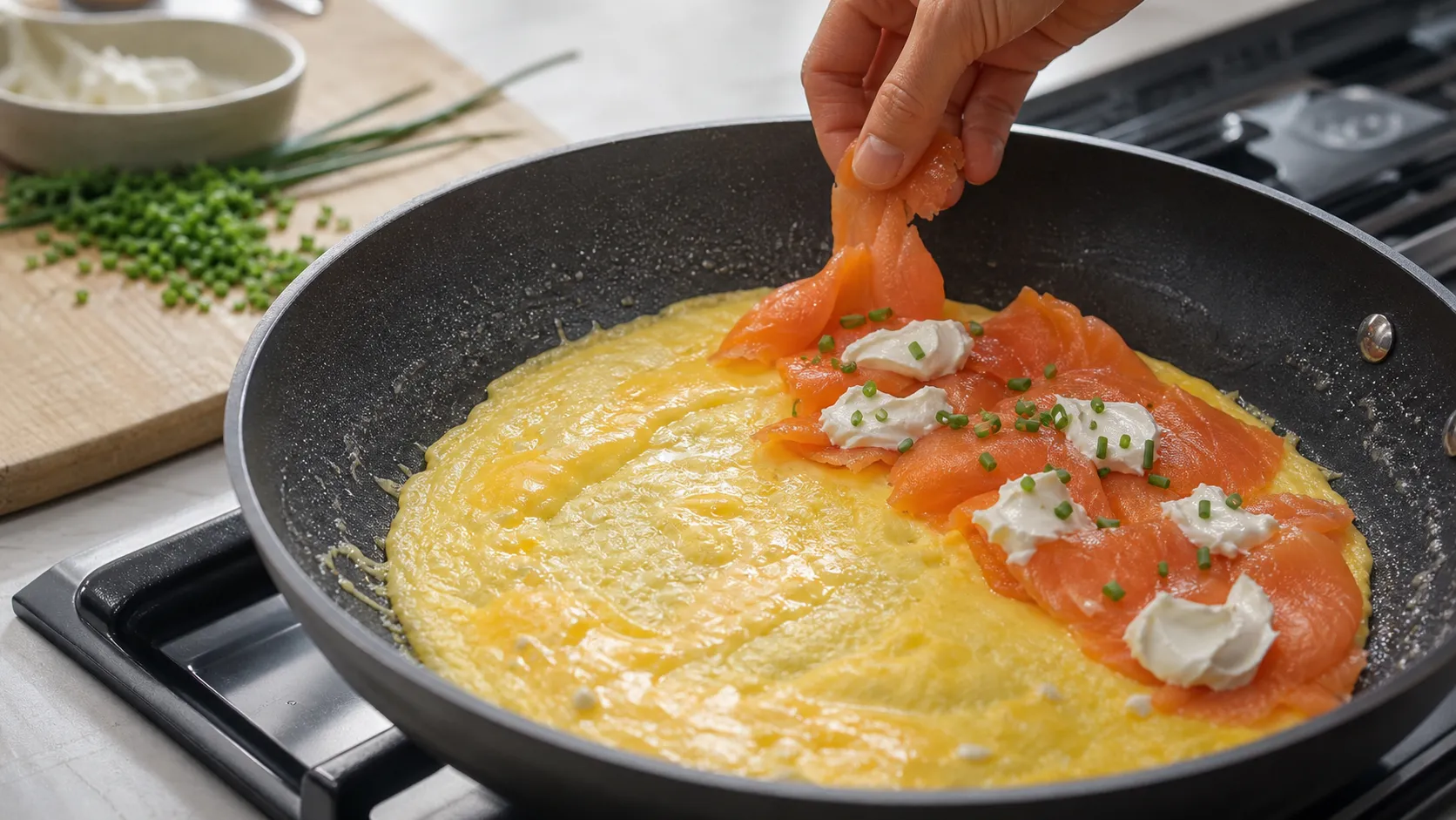Eimasse stockt in der Pfanne, Frischkäse und Räucherlachs liegen zum Belegen bereit