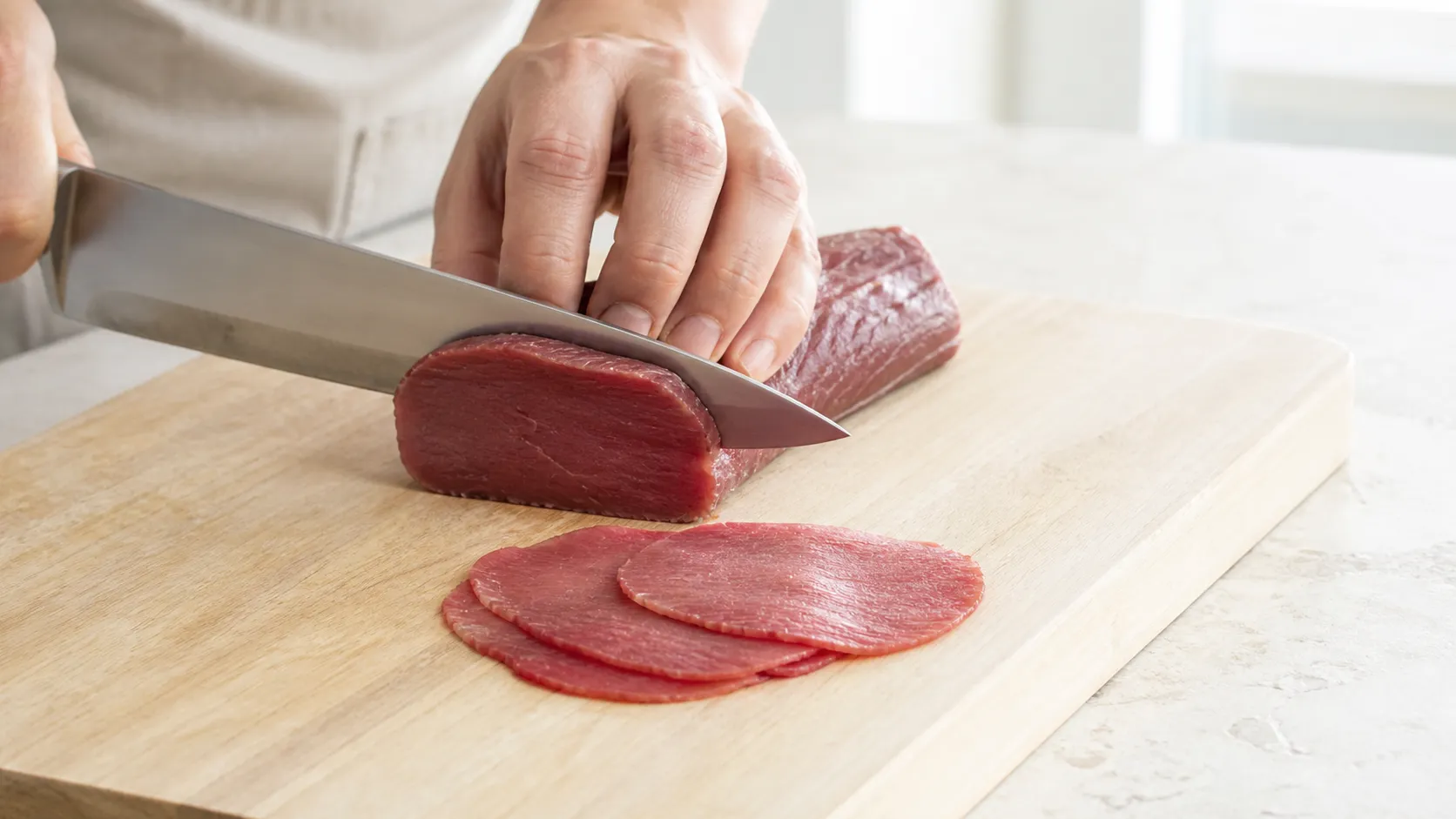 Leicht angefrorenes Rinderfilet wird mit einem langen Messer quer zur Faser in hauchdünne Carpaccio-Scheiben geschnitten