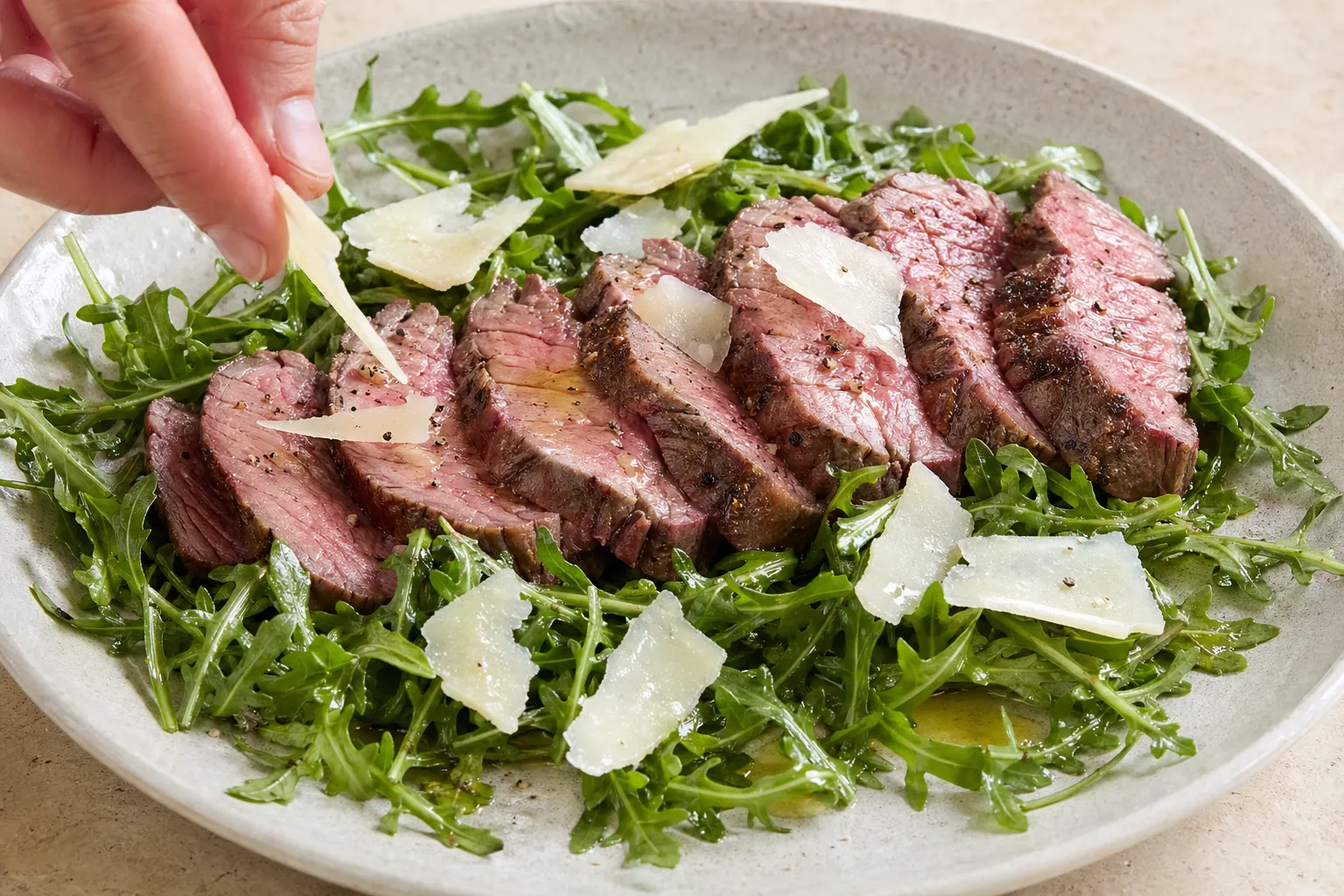 Keto-Teller mit in Scheiben geschnittenem Rinderfilet auf Rucola mit Parmesan und Olivenöl anrichten