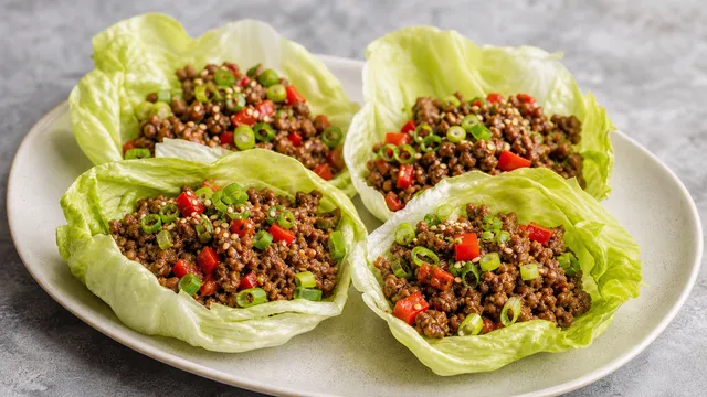 Keto Rindfleisch-Lettuce-Wraps mit gebratenem Rinderhack, roter Paprika und Frühlingszwiebeln in Eisbergsalatblättern