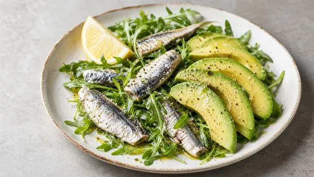 Keto Sardinen-Avocado-Salat mit Sardinen in Olivenöl, Avocado, Rucola und Zitrone auf einem Teller