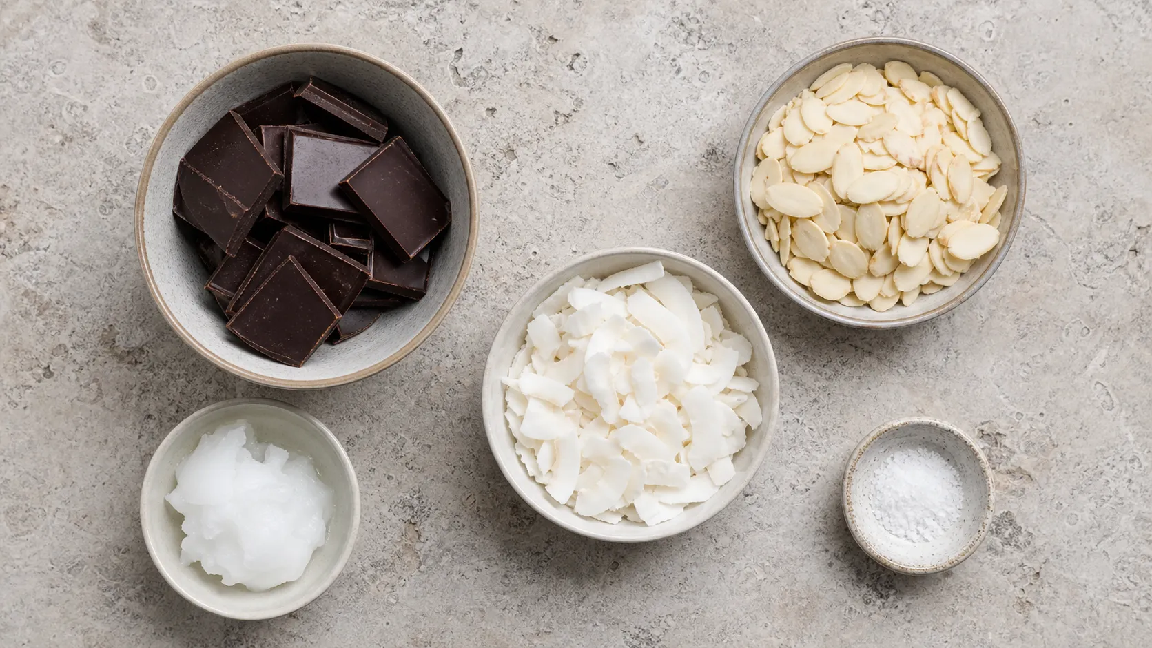 Zutaten für Keto-Schoko-Crossies: zuckerfreie Zartbitterschokolade, Mandelblättchen, Kokoschips und Kokosöl