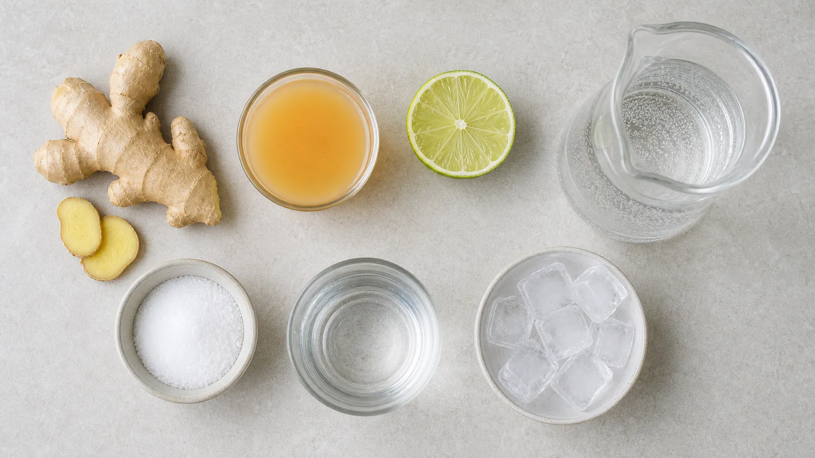 Flatlay der Zutaten für Keto-Switchel mit Ingwer, Apfelessig, Limette, Erythrit, Mineralwasser und Eiswürfeln