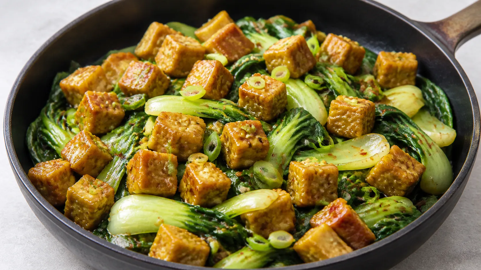 Pfanne mit goldbraunen Tempeh-Würfeln, Pak Choi, Ingwer und geröstetem Sesam