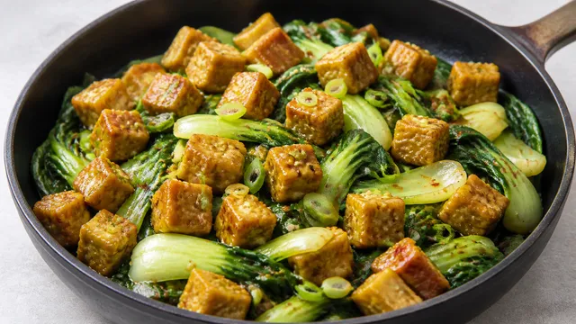 Pfanne mit goldbraunen Tempeh-Würfeln, Pak Choi, Ingwer und geröstetem Sesam
