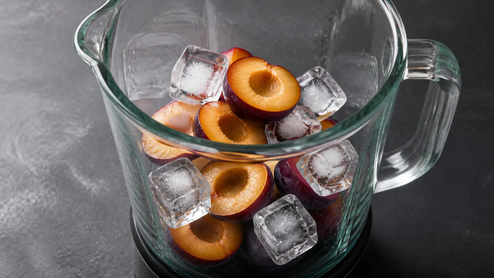 Entsteinte Zwetschgenhälften und Eiswürfel im Mixbecher, kurz vor dem Mixen